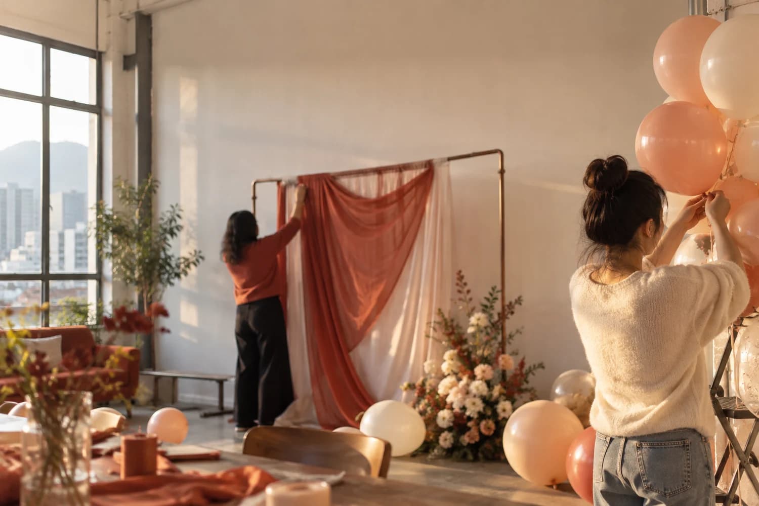 Two people tying balloons and putting up birthday decorations in a party room