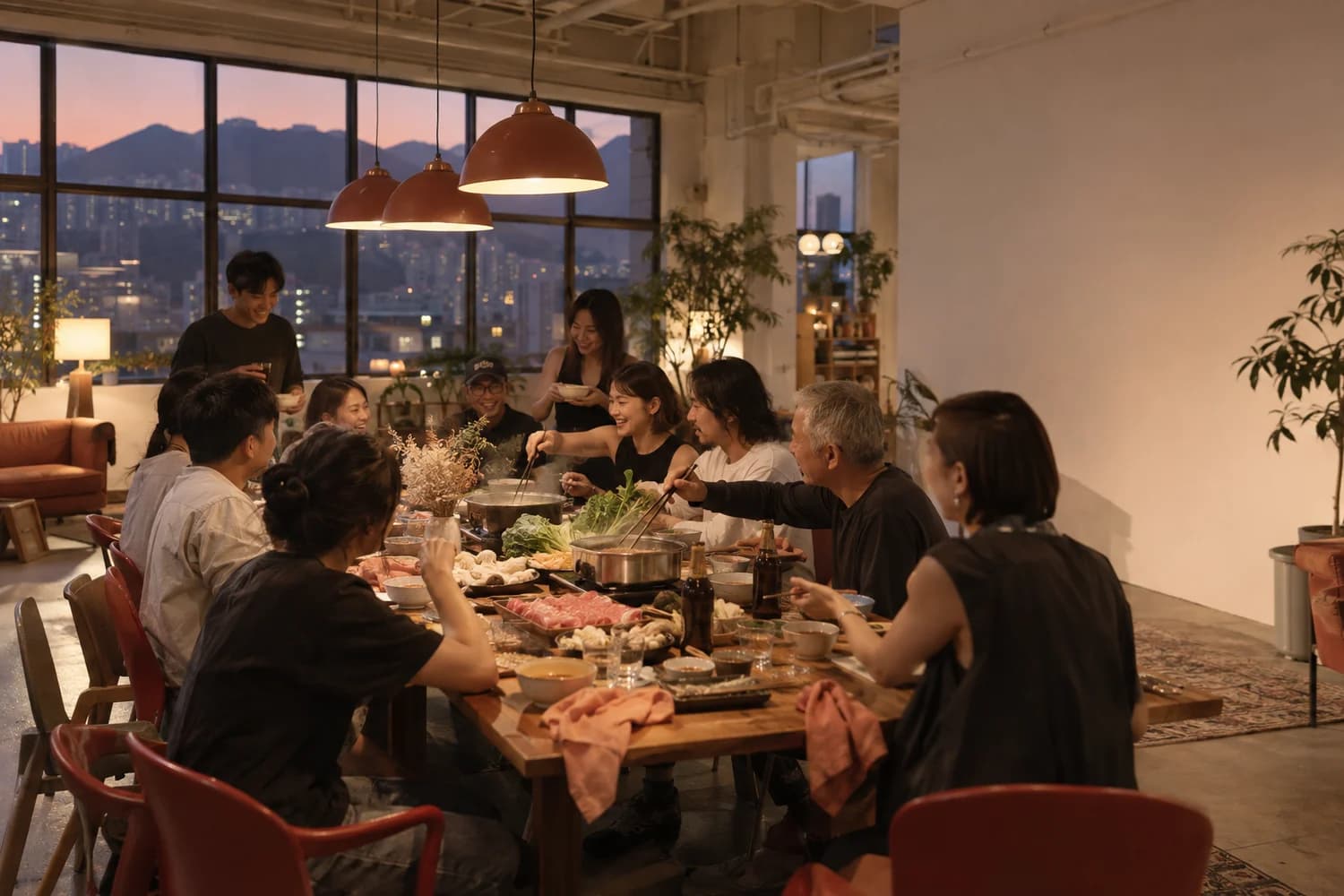 寬敞嘅工廈 party room，長枱上擺滿火鍋同小食，一班人圍住傾偈