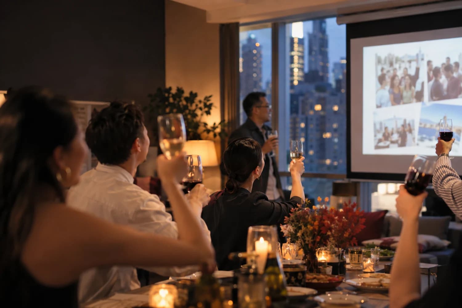 Colleagues raising glasses in front of a projected slideshow in a commercial-building party room