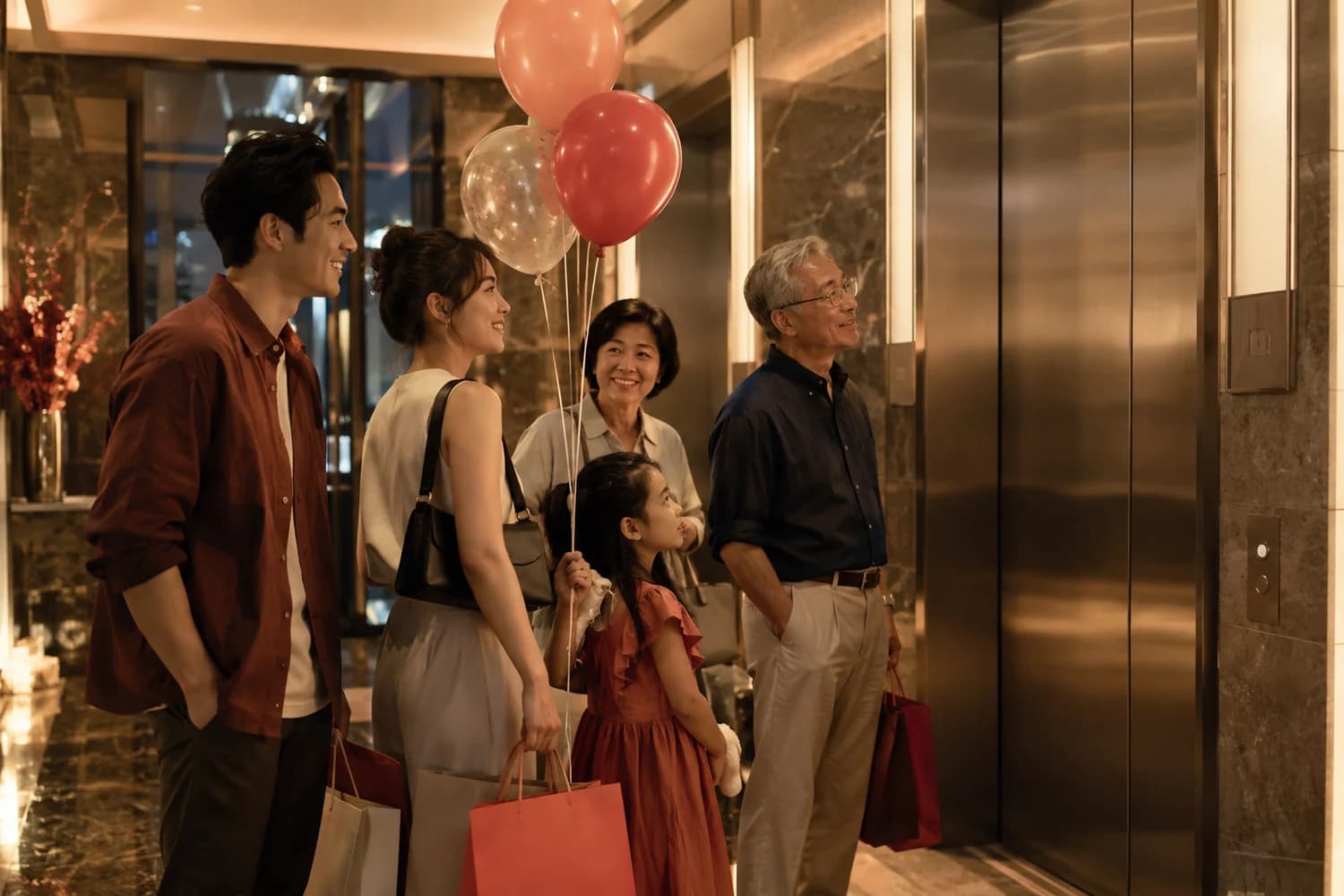 Friends waiting with party supplies in a Chai Wan industrial building lift lobby